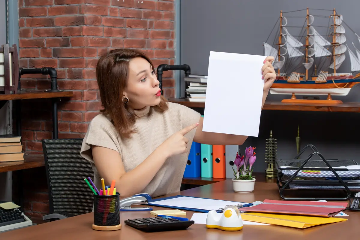 Front view surprised woman pointing at papers sitting at wall