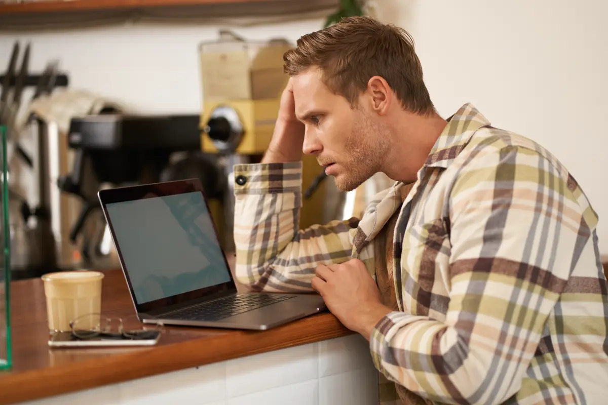 Image of adult man looking complicated at laptop screen staring puzzled at his monitor doing