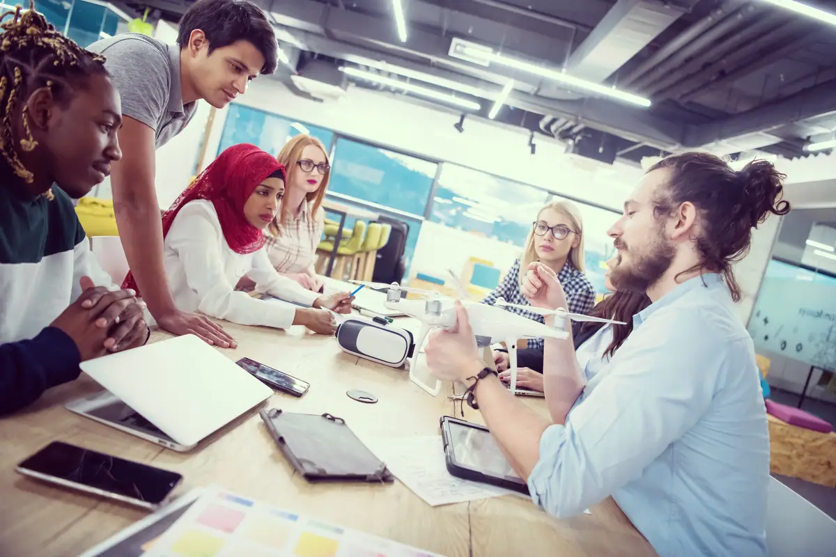 multiethnic startup business team discussing new business plan,working on laptop and tablet computer while learning about drone technology for new business advancement
