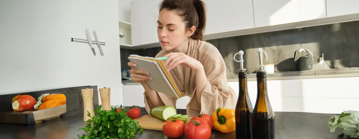 Portrait of woman checking grocery list looking at vegetables holding notebook reading recipe while