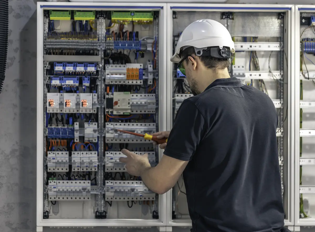A male electrician works in a switchboard using an electrical connection cable