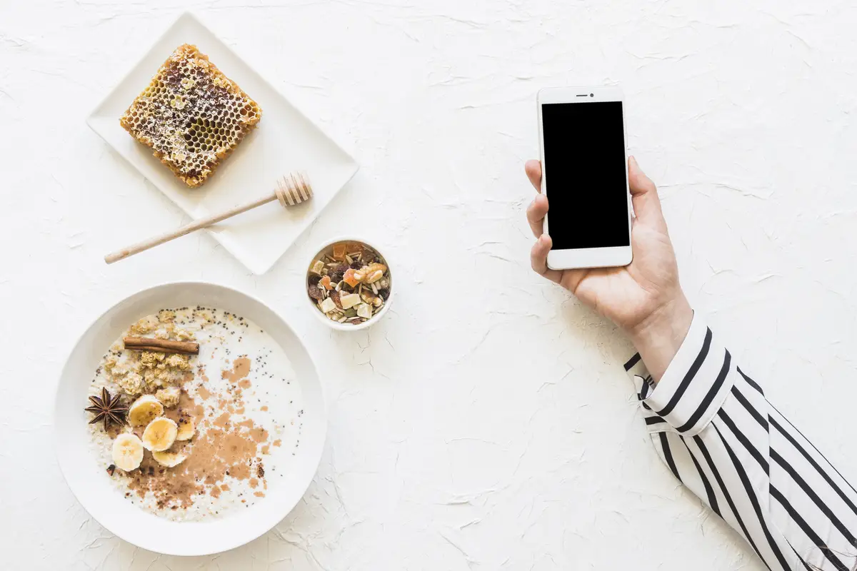 Oatmeals; dryfruits and honeycomb on table with cellphone in hands