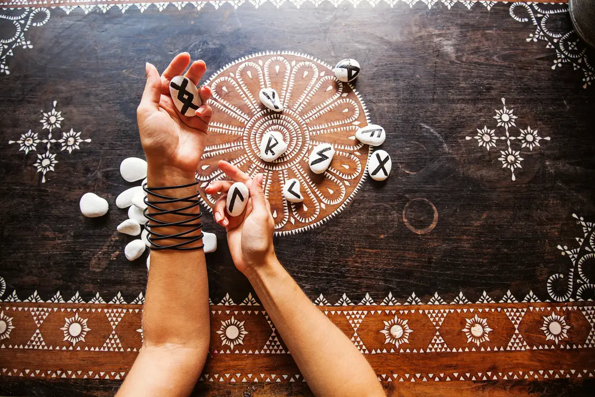 Hands holding runes stones on an ornate table