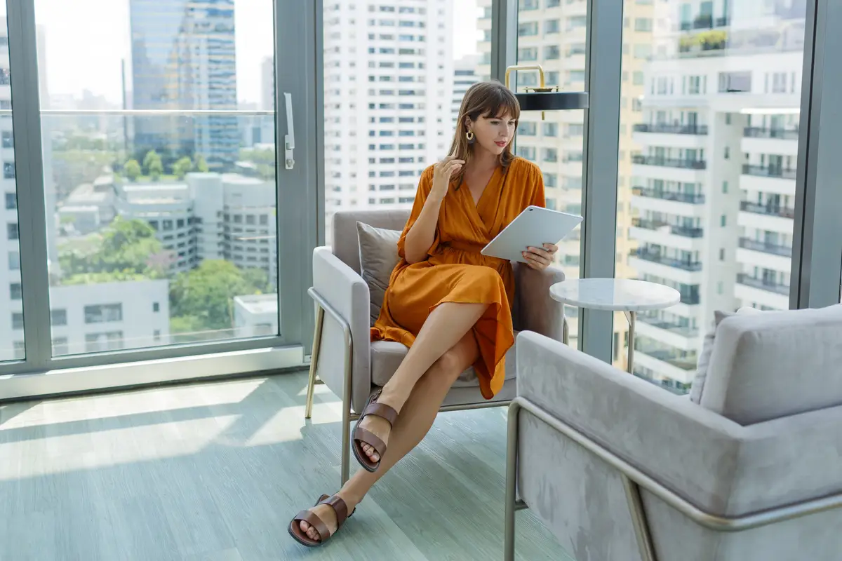 Beautiful woman in orange dress using tablet in modern rooftop office.