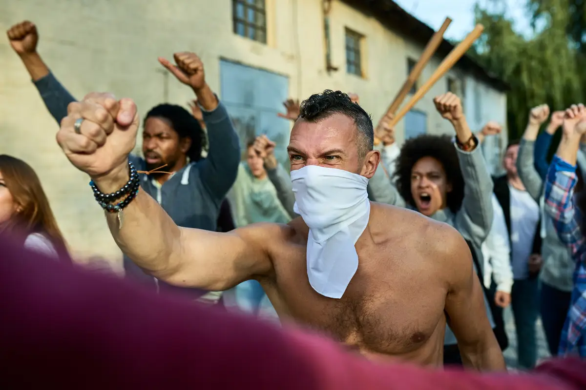 Rebellious man with face mask protesting with crowd of people on city streets
