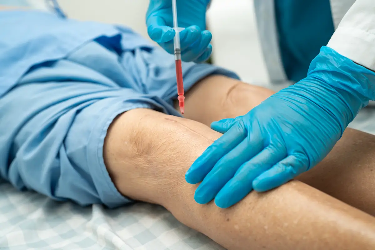 Asian doctor inject Hyaluronic acid platelet rich plasma into the knee of senior woman