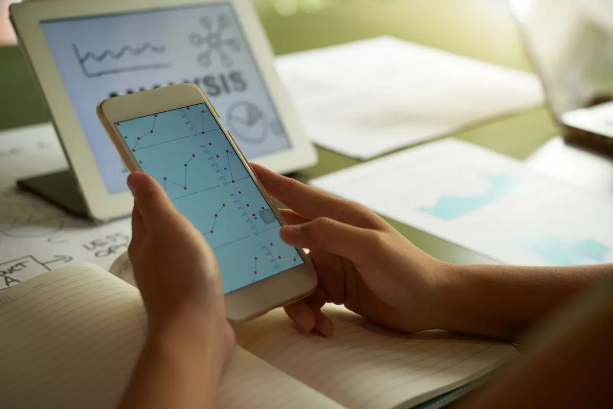 Cropped unrecognizable person analysing financial chart on smartphone