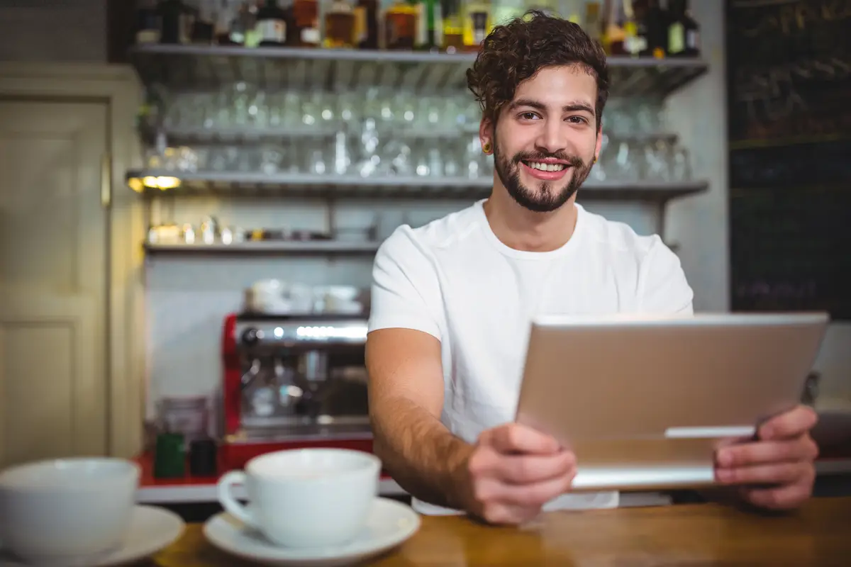 Smiling barista holding a tablet in a coffee shop
