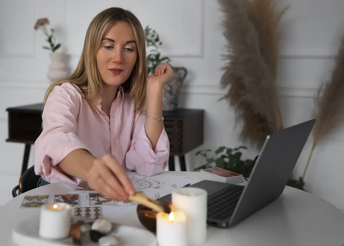 Medium shot woman reading tarot with laptop