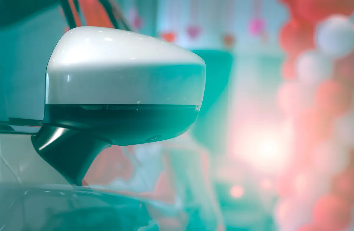 Close-up rear view wing mirror of luxury car on blurred background of modern showroom