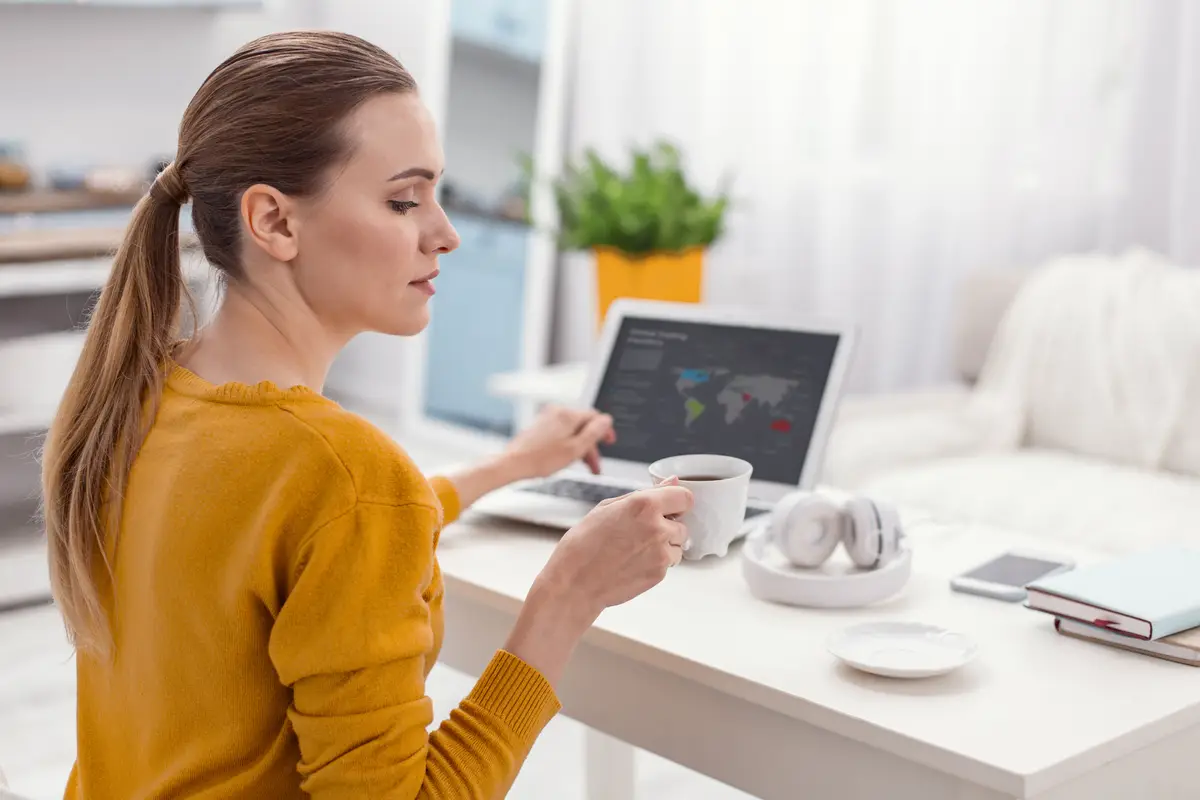 Lets work. Ambitious focused skillful businesswoman drinking coffee while posing in profile and working