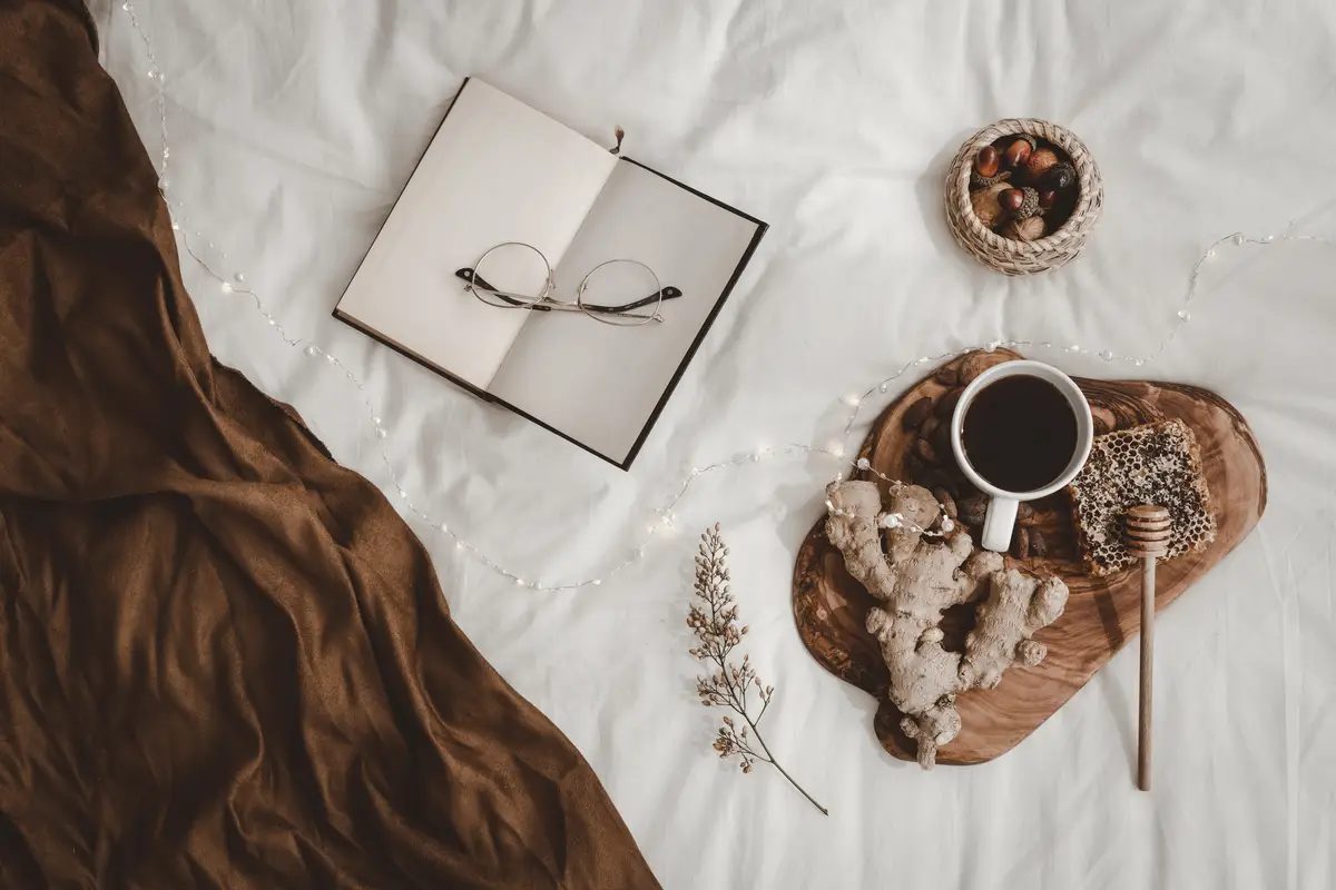 Opened book with glasses near beverage and snacks
