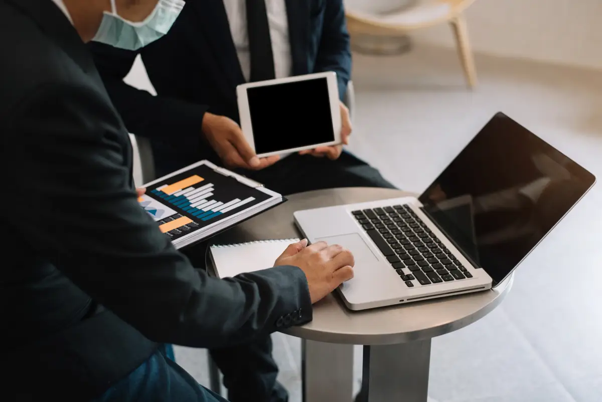 Team or financial data analysts working with tablets and laptop computers and data graphs