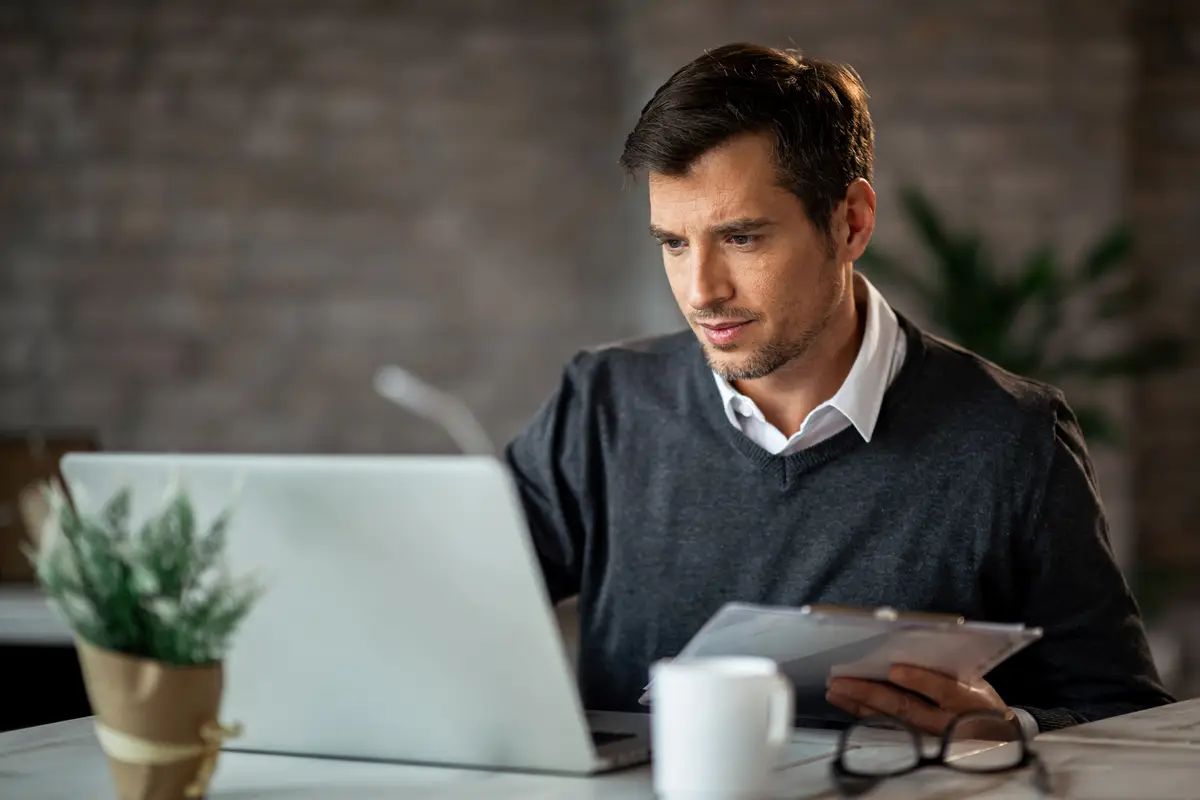 Mid adult businessman entering data from business reports in a computer at the office