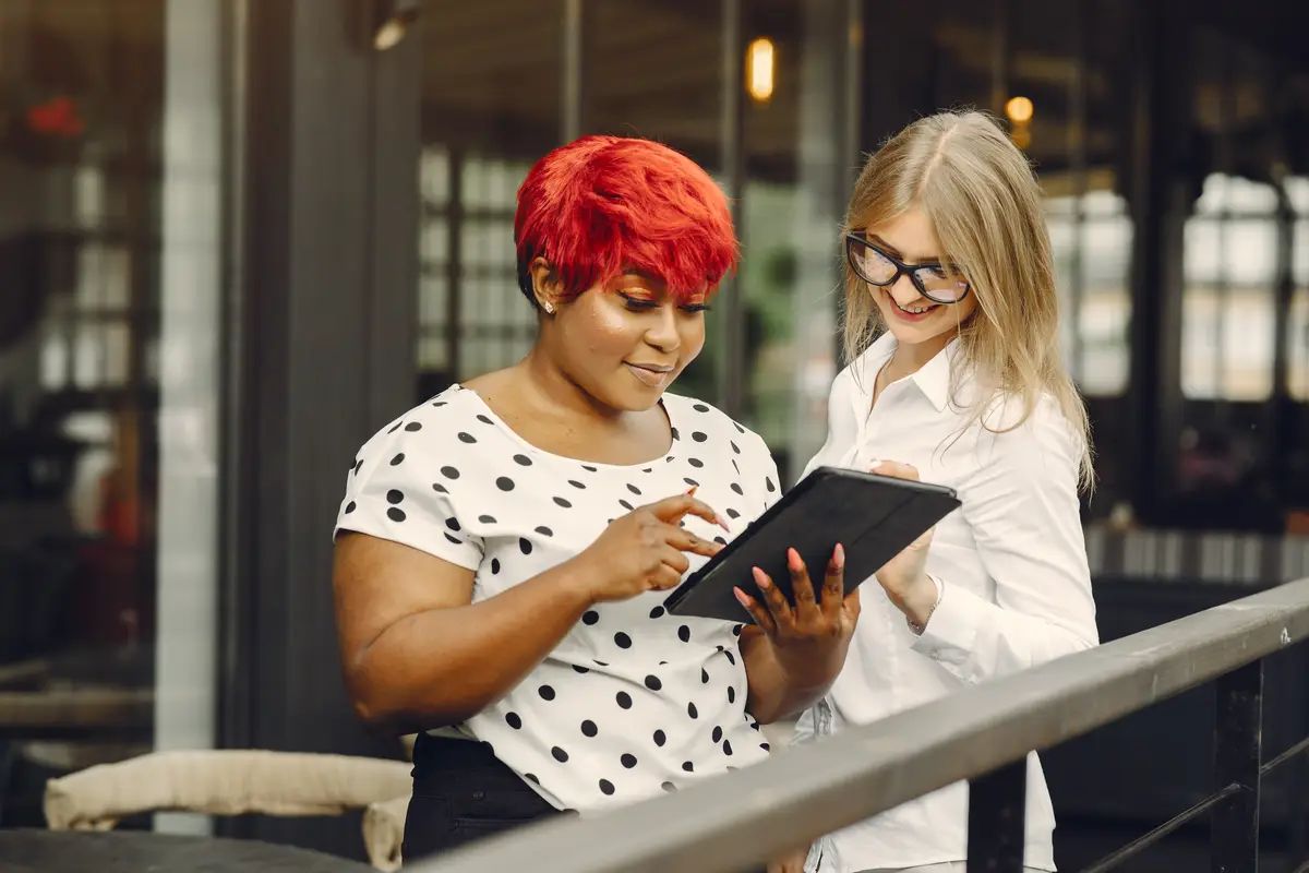 Young African American female working in an office. Lady in a white blouse. Caucasian woman with her african colleague.