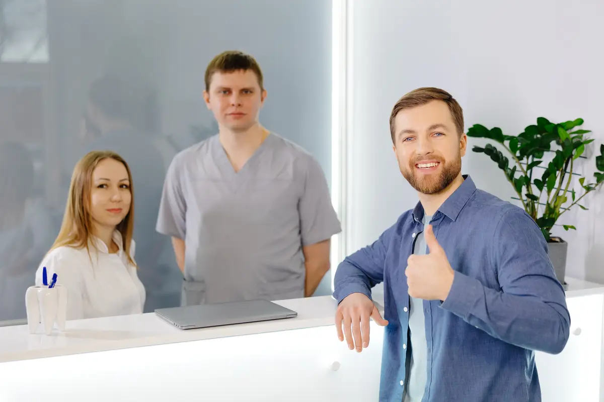 Grateful patient Man standing at the reception of dental clinic and very pleased for the treatment