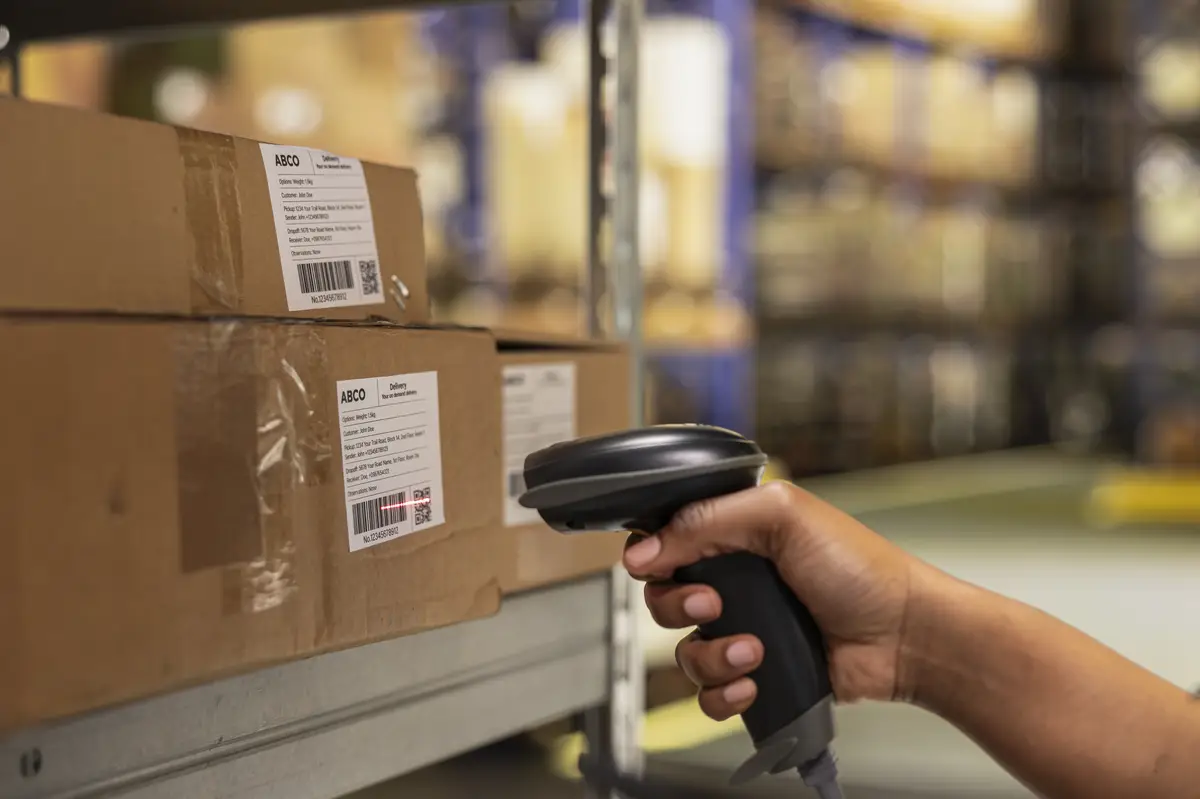 Close up of black woman worker scanning packages in a large storehouse registering airway bills