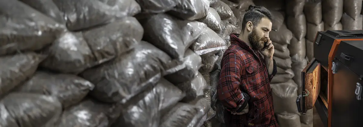 A man with a solid fuel boiler working on biofuel economical heating