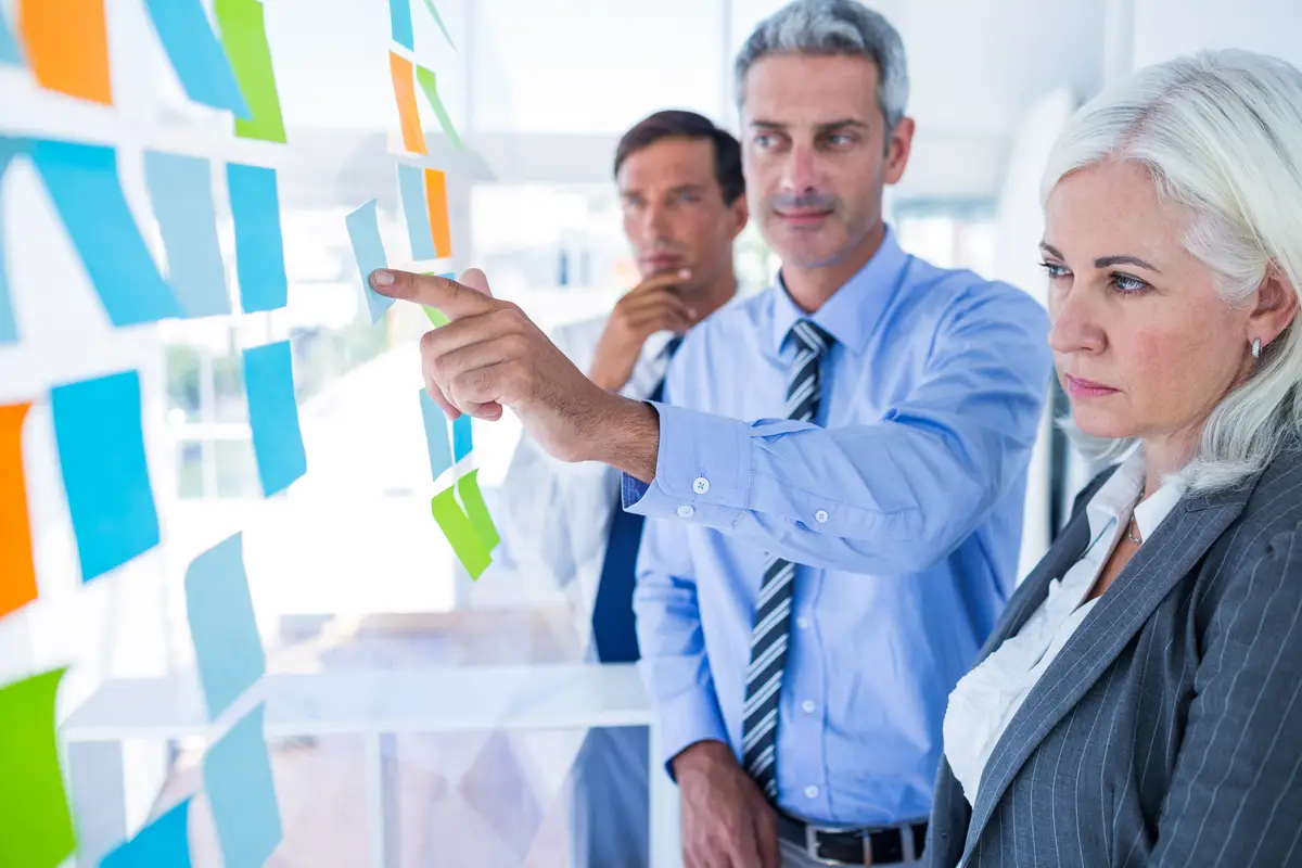 Business people looking at post it on the wall 