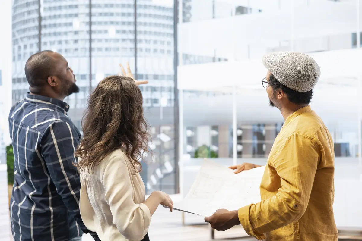 Business clients and broker salesman examining blueprints and layout