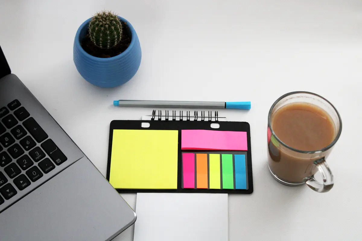 notebook with pen are on top of wood office desk table with cup of coffee and office supplies