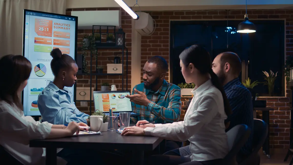 Coworkers brainstorming, african american team analyst showing revenue statistics on laptop screen. People planning strategy in business meeting, discussing analytics presentation