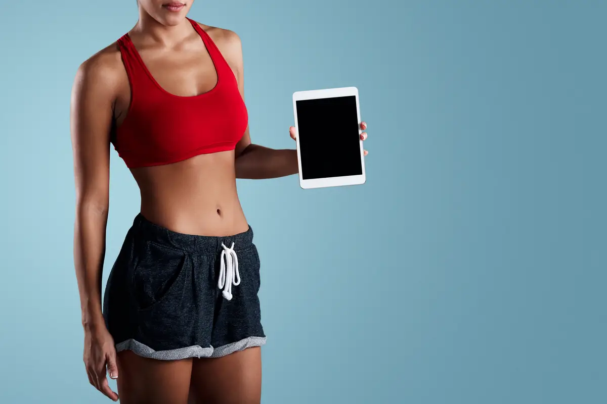 Fit woman in sportswear holding tablet