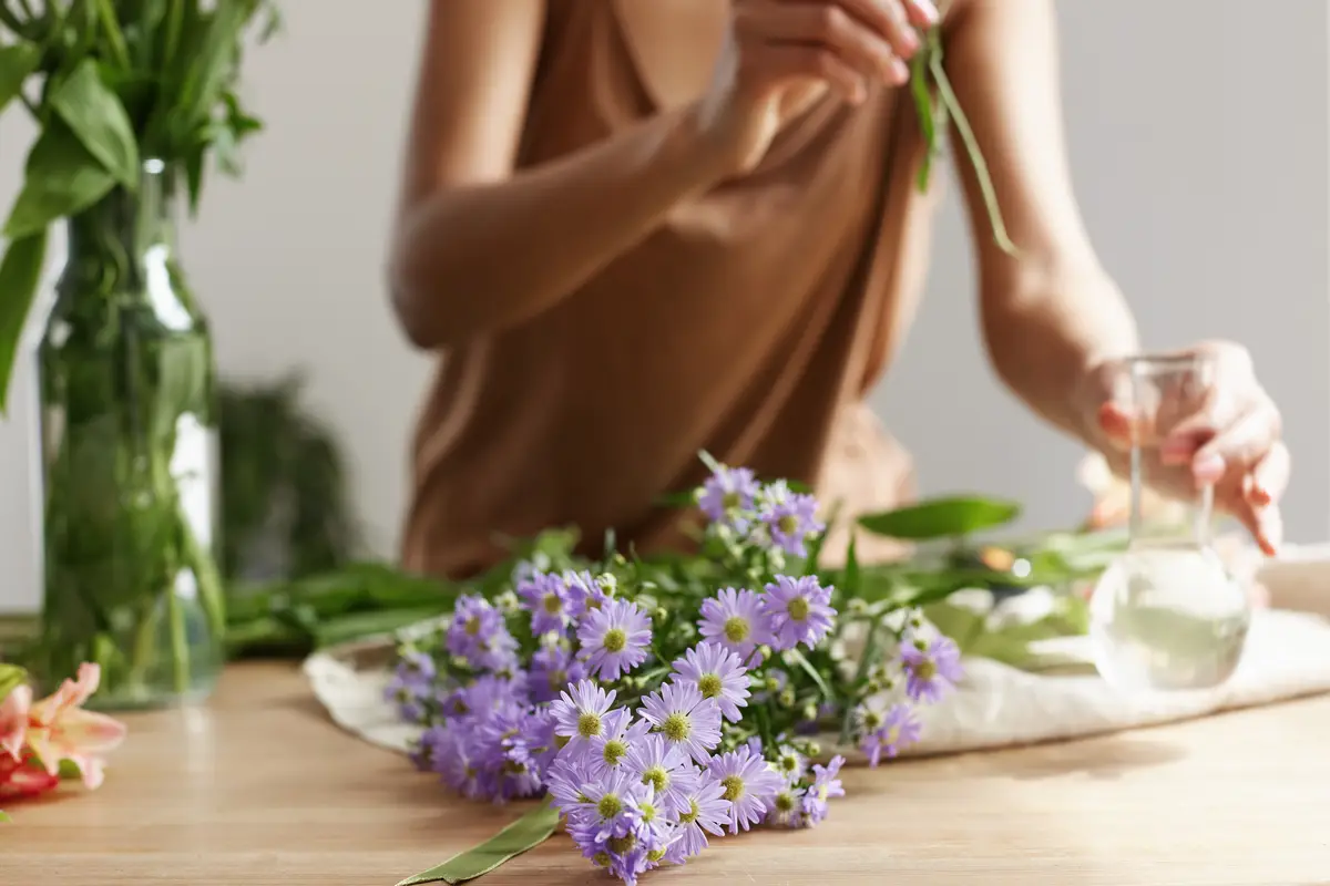 Close up of florist hands making bouquet of flowers at workplace.