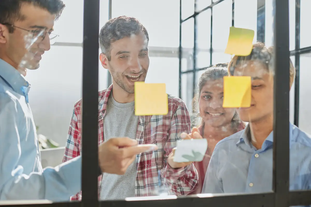 A group of business people behind a glass wall in the office sticking notes