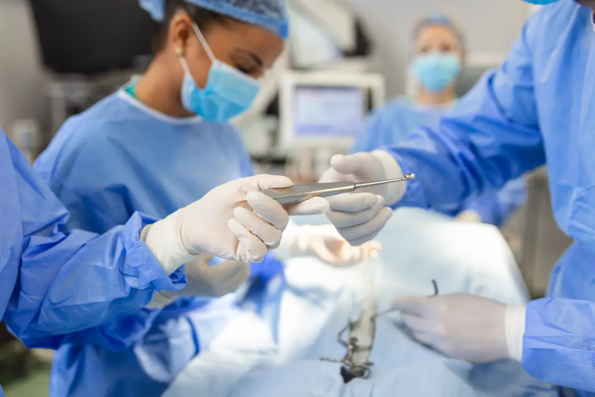 Diagnóstico diferencial e manejo das infecções osteoarticulares profundas 3 Low Angle Shot in the Operating Room Assistant Hands out Instruments to Surgeons During Operation Surgeons Perform Operation Professional Medical Doctors Performing Surgery