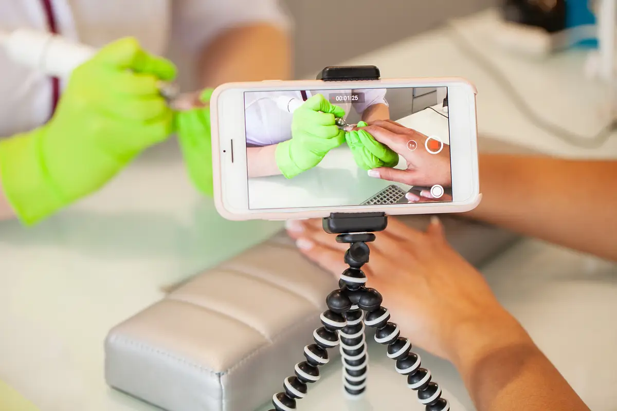 Manicure procedure video videoshooting on phone. Skillful master of manicure holding file in her hands while working in her beauty salon.