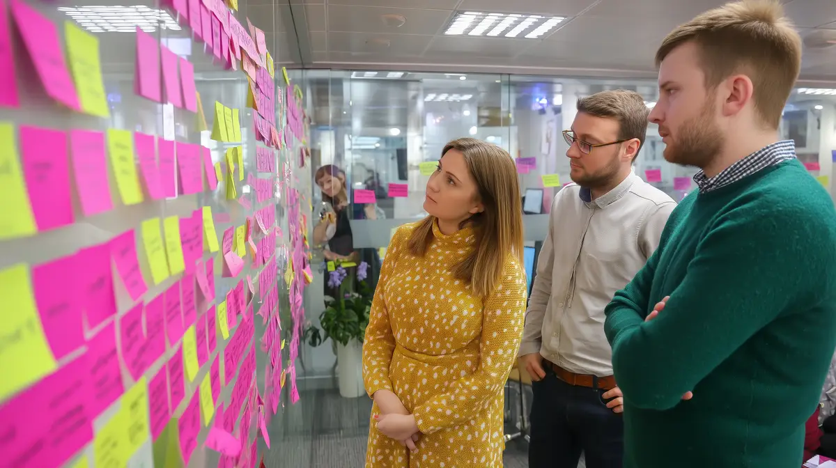 Team brainstorming session with sticky notes on glass wall in modern office setting during work hours