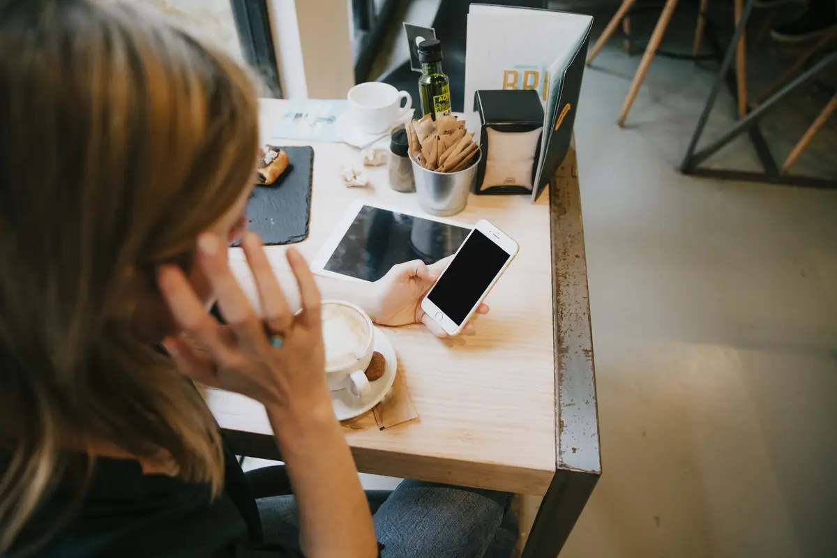 Unrecognizable woman browsing smartphone in cafe