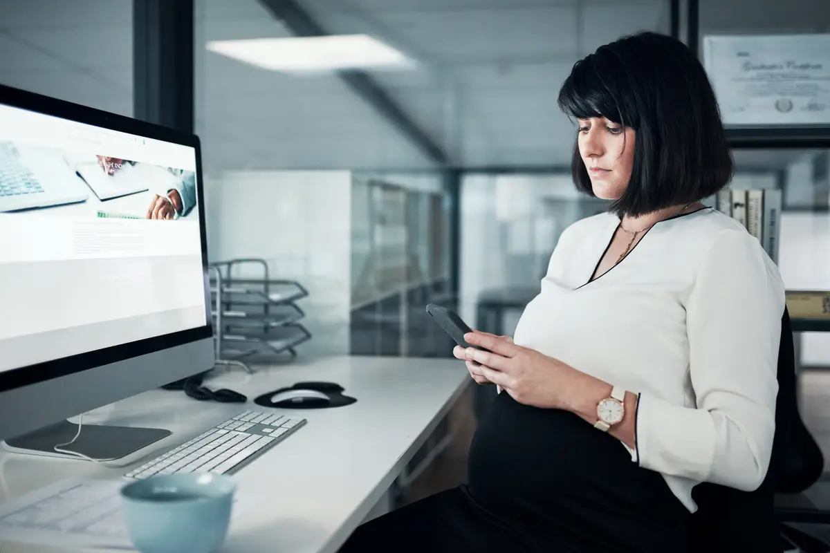 Woman serious and pregnant with smartphone at office on internet or website for booking or consultation for gynecologist Female person fertility and texting as employee on pregnancy app for health