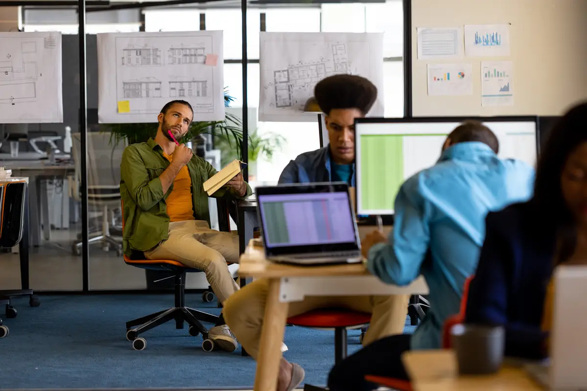 Thoughtful male creative and colleagues working at computers in office. Casual office, teamwork, communication, business and work, unaltered.