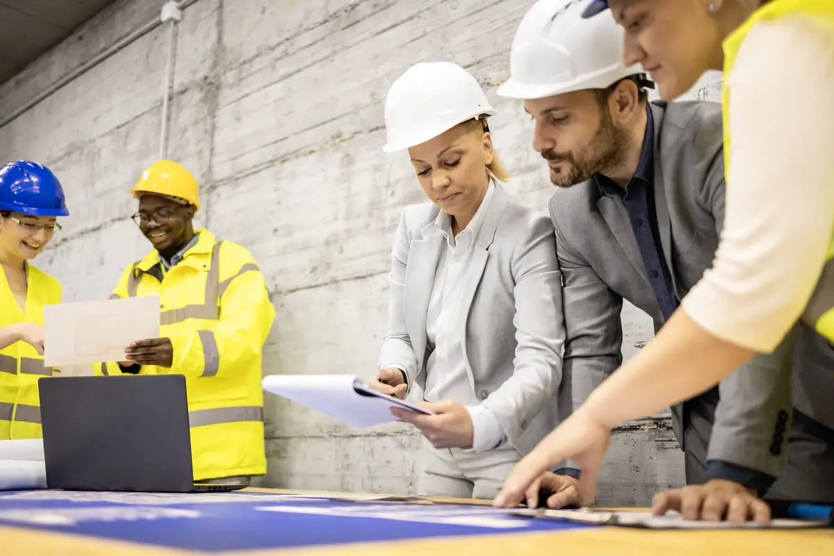 Team of experienced architects and civil engineers analyzing building plans at construction site