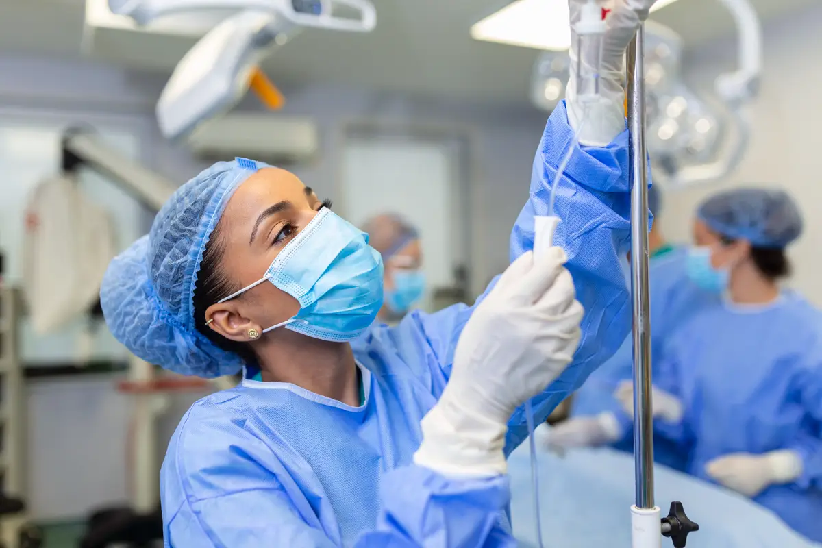 African american female Doctor in the operating room putting drugs through an IV surgery concepts
