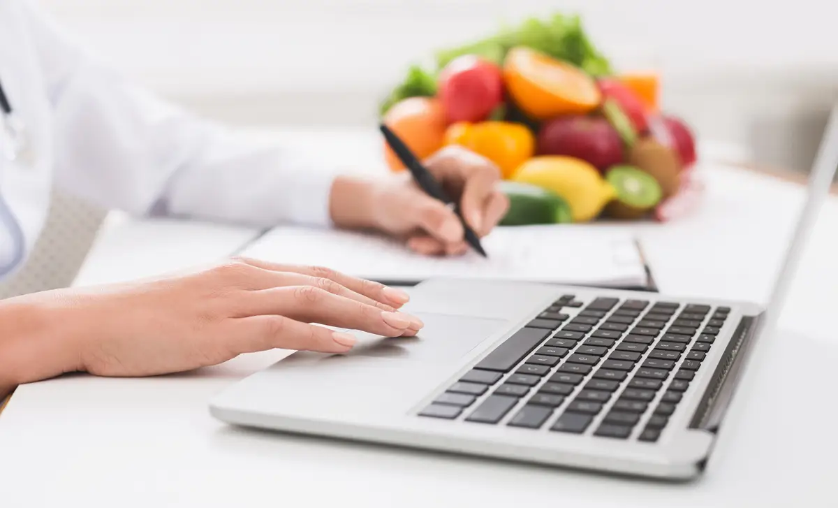 Nutritionist doctor writing diet plan on table