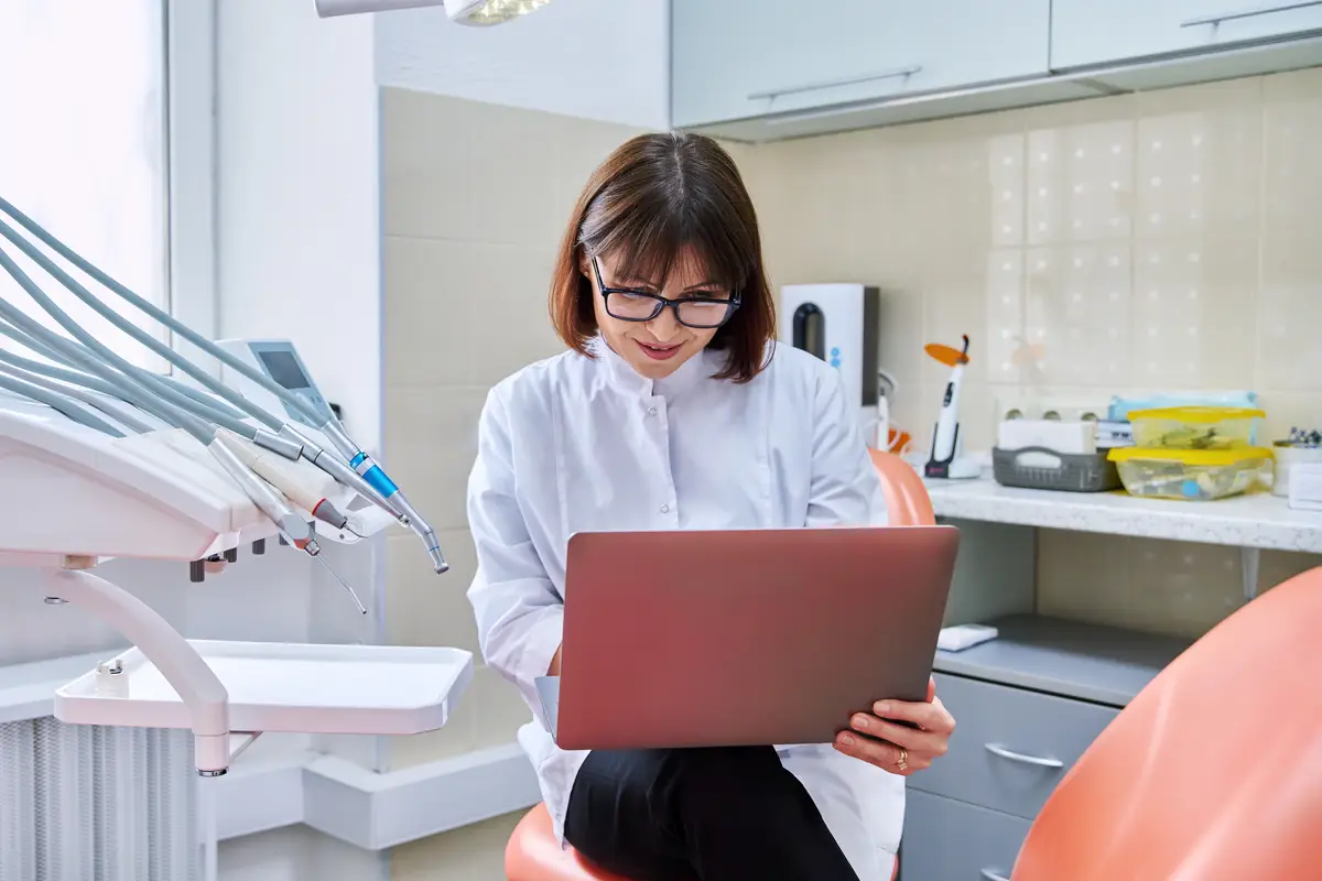 Doctor dentist sitting in the office using a laptop