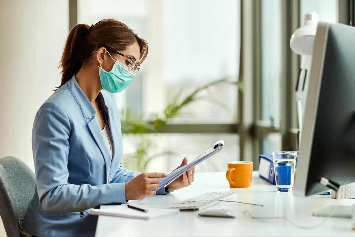 Anuidades CFMV 2026: valores, cadastro e regularização empresarial 2 Young businesswoman wearing protective face mask while going through reports and working in the office