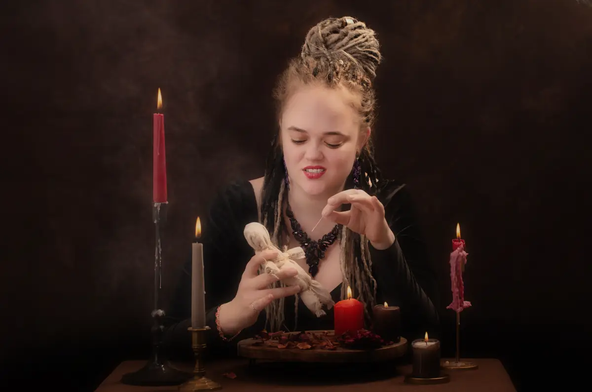 Young witch with dreadlocks on dark background