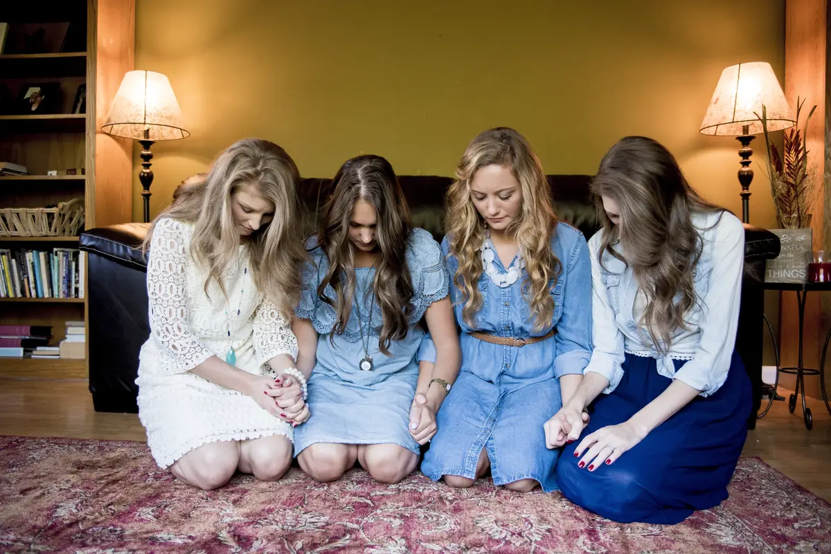 Young girls next to each other looking down in a room