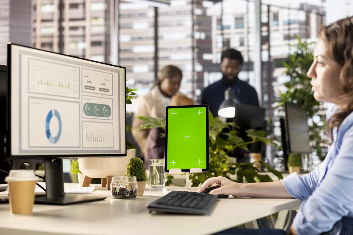 Professional employee works at desk with green screen in a corporation