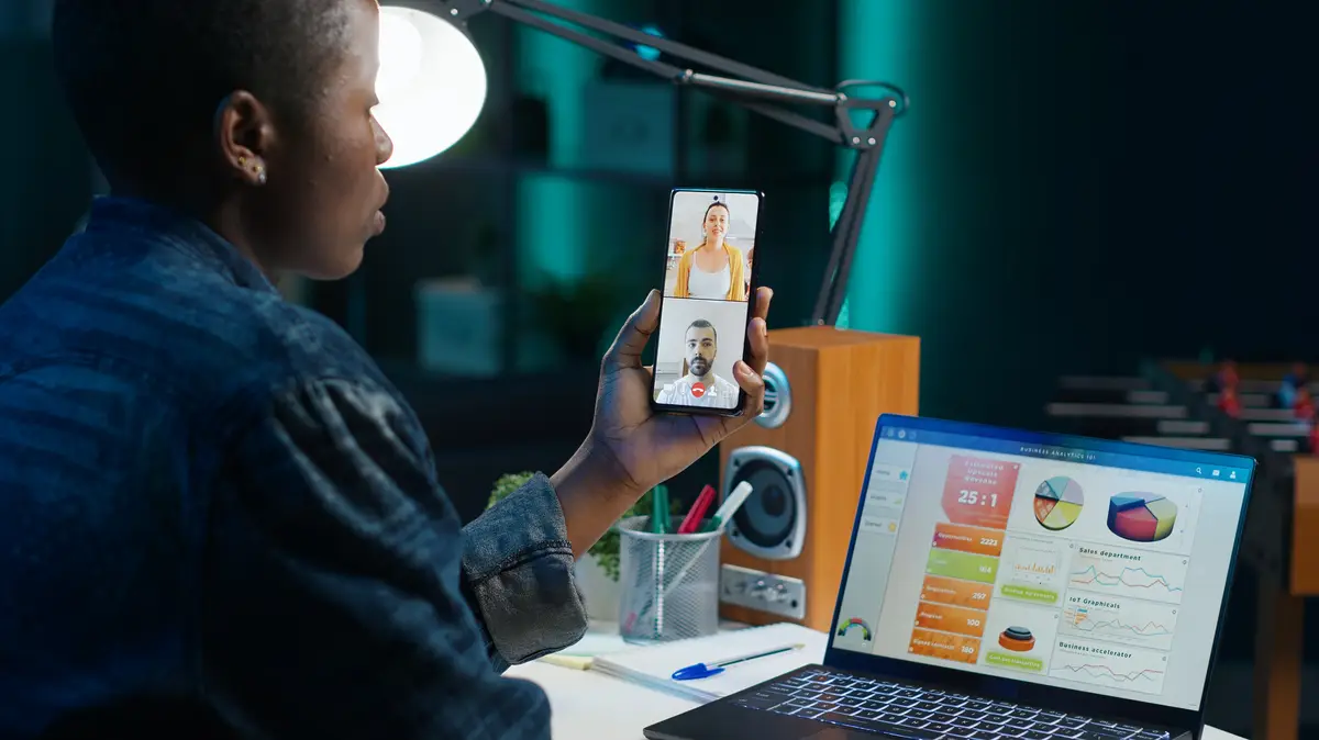 Team leader in online videocall with workers using mobile phone