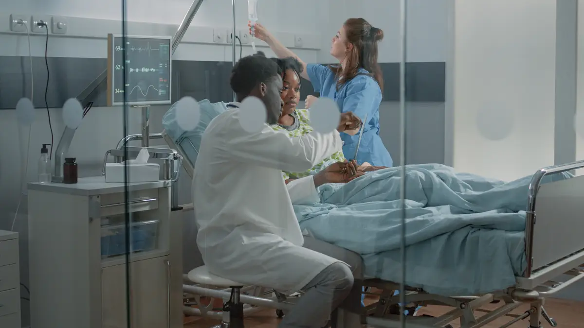 Contágio e prevenção da tuberculose pulmonar em hospitais 4 Man working as medic and explaining x ray scan results to patient with IV drip bag in hospital ward bed. Medical specialist holding radiography to talk to young woman about healthcare