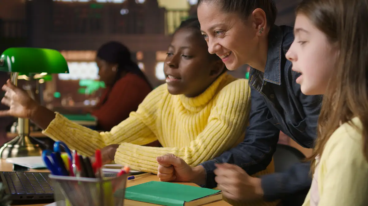 Multiethnic scholars in the library engaged in remote learning with their mentor