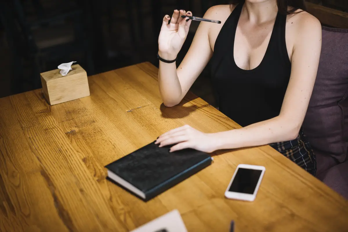 Close-up of a woman with diary and cell phone on table at restaurant