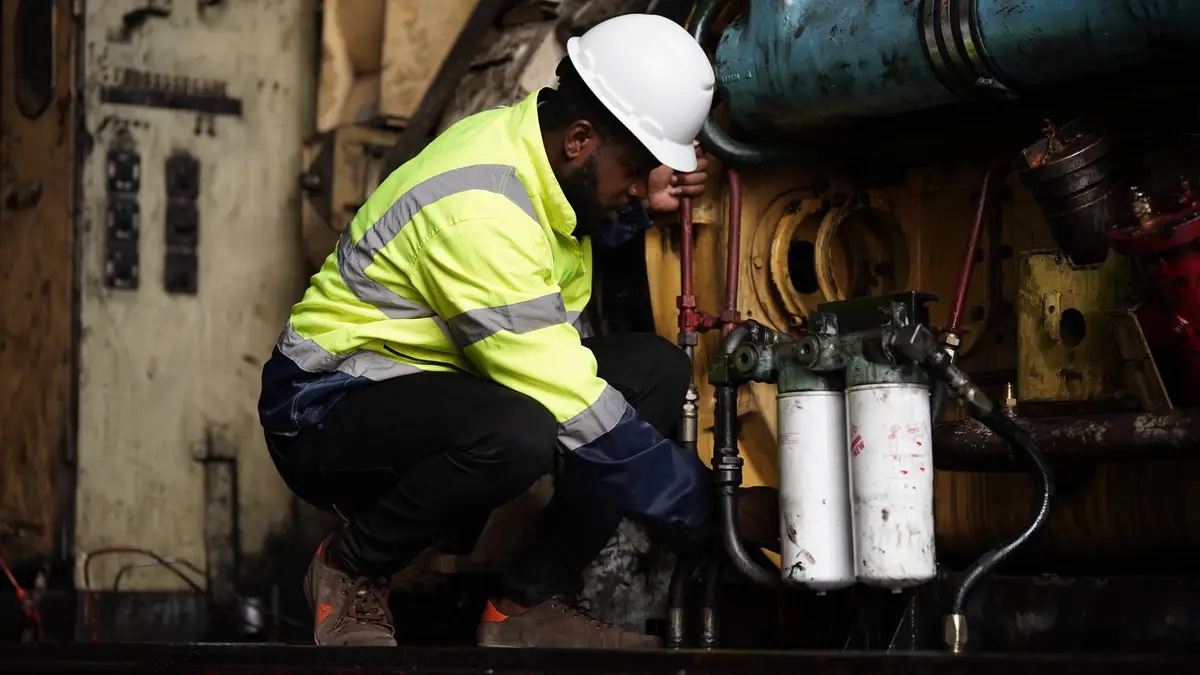 Engenheiro de manutenção em oficina técnica industrial inspecionando equipamentos elétricos