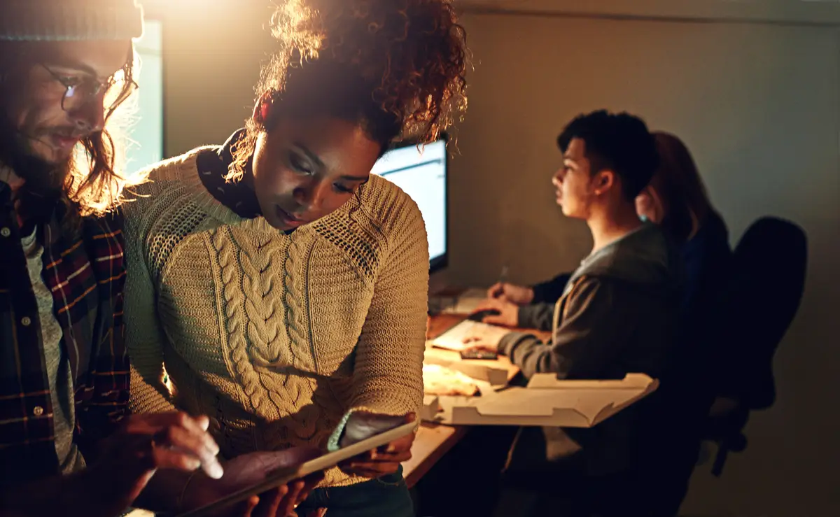 Collaboration tablet and research with people in office at night for planning web design and strategy Creative teamwork and technology with man and woman in startup for data proposal and idea