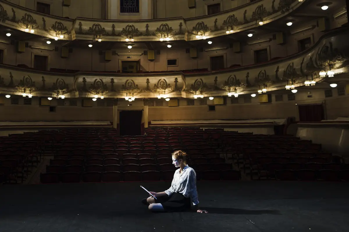 Mime reading manuscript on stage in empty auditorium